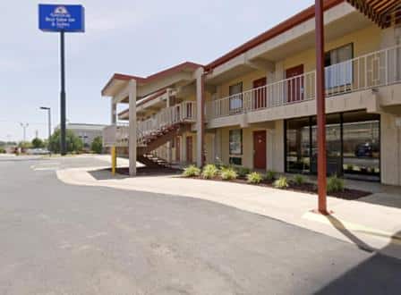 America's Best Value Inn & Suites in Conway Arkansas. A beige building with reddish-brown doors and roof with a blue sign.