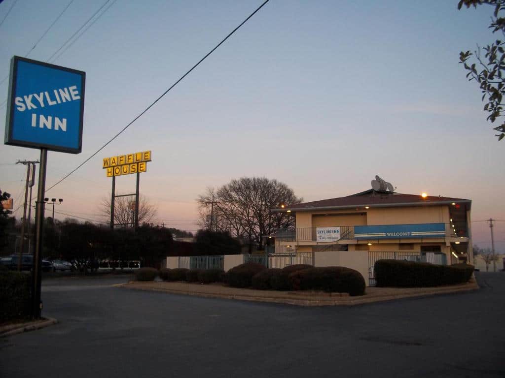 A blue sign that says "Skyline Inn" stands in front of a small beige building with a blue banner that says "welcome" in Conway, Arkansas. A waffle House sign is to the left of the building.