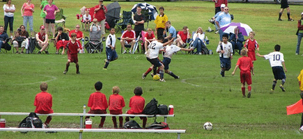 Two teams of young boys, one in white and one in red, play a soccer game at Centennial Soccer Complex in Conway, Arkansas.