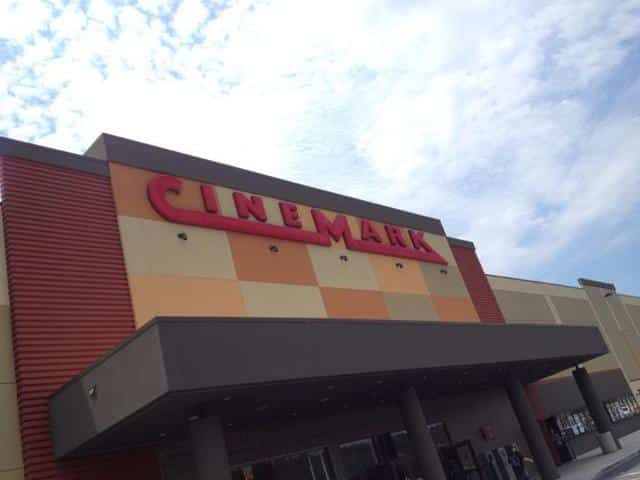 The Cinemark sign on the movie theater in Conway, Arkansas that sits above a black awning on a brown and gray checkered background.